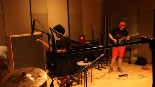 Two guitarists warming up between microphone stands in a studio live room
